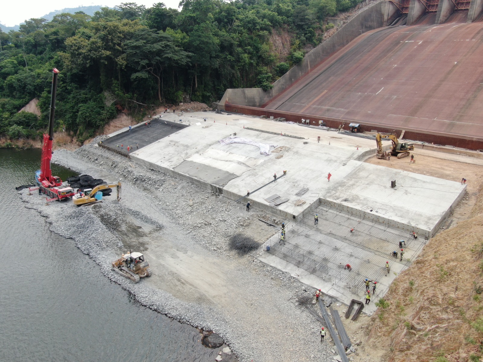Aerial view of crane and construction crews working at the base of Akosombo Dam