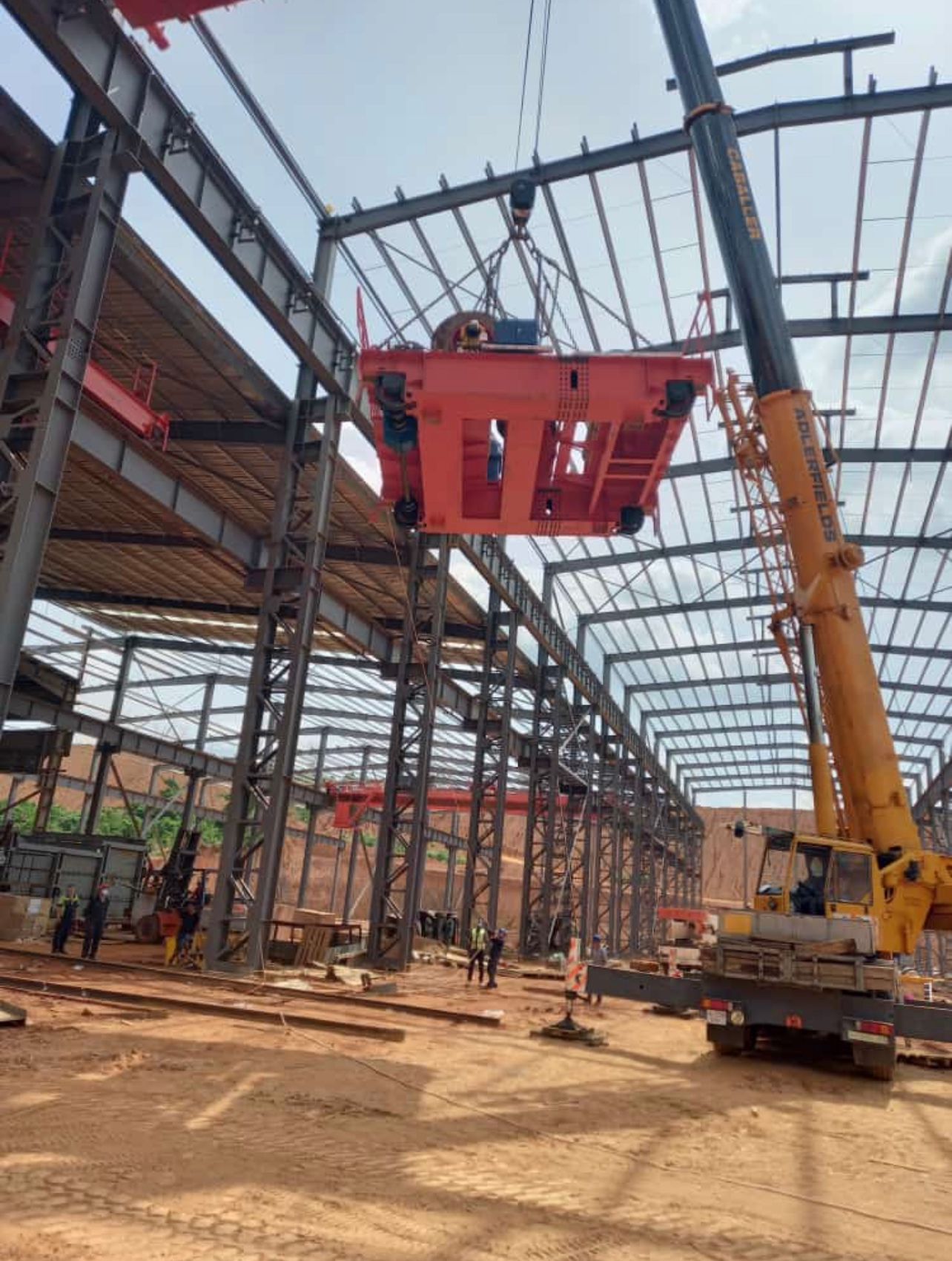 Crane installing an overhead bridge in an industrial facility